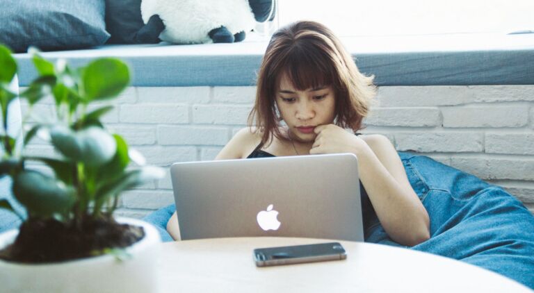 Jeune femme concentrée travaillant sur un ordinateur portable à la maison, adoptant un style de vie de télétravail.