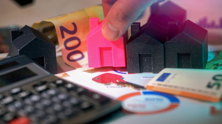 Maisons miniatures, billets en euros et calculatrice représentant un investissement immobilier.