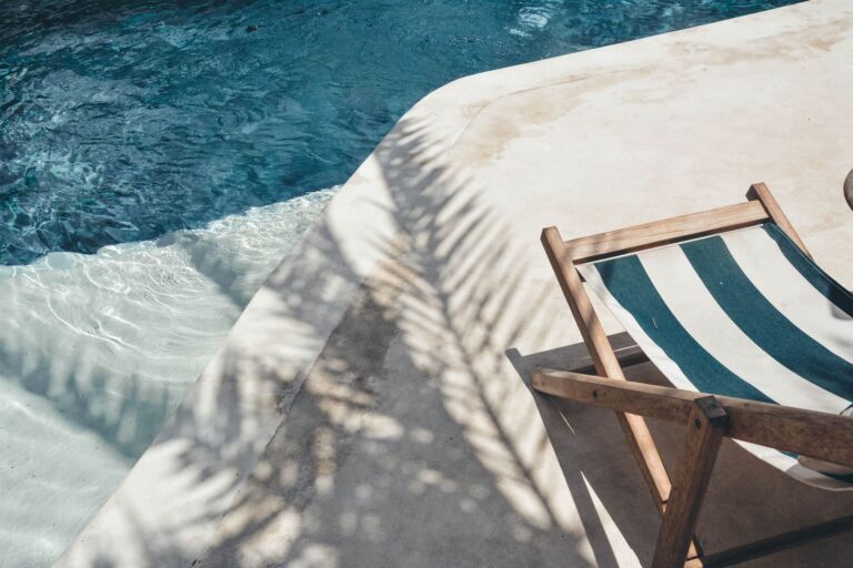 Chaise longue sereine au bord de la piscine avec des ombres de palmier, parfaite pour se détendre en été à Bali.