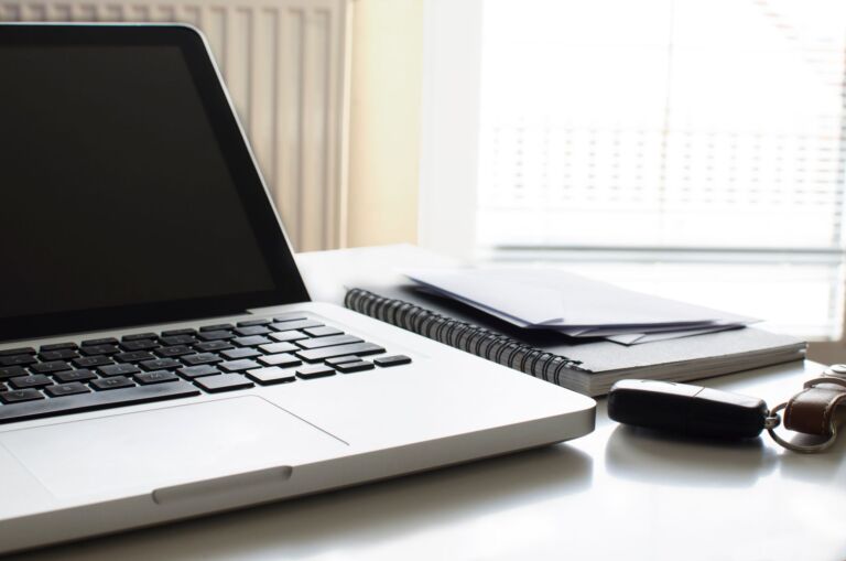 Aménagement de bureau contemporain avec un ordinateur portable, un carnet, des enveloppes et des clés de voiture sur un bureau.