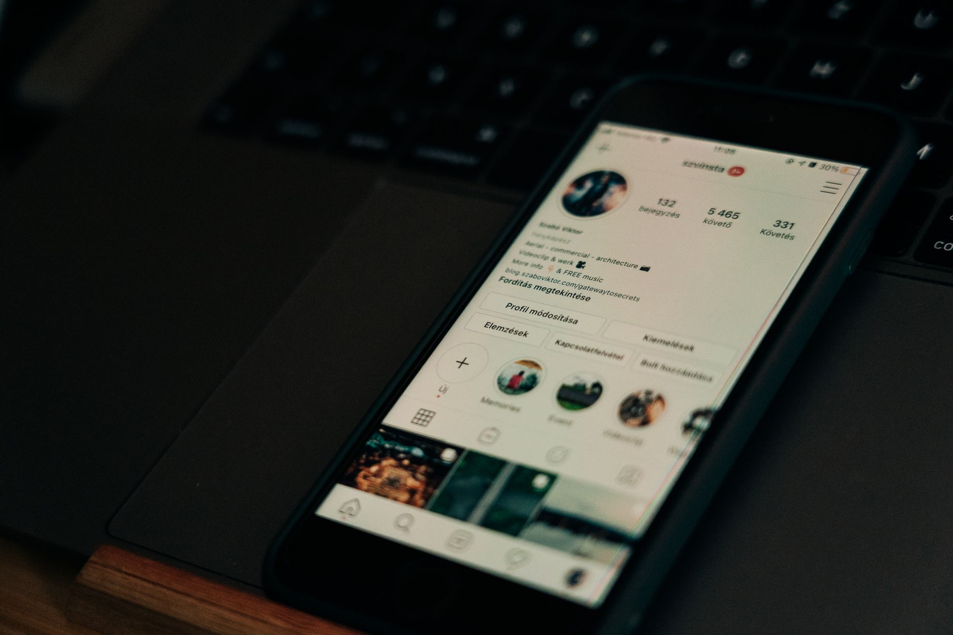 Gros plan sur un smartphone affichant un écran de profil de médias sociaux à côté d'un ordinateur portable.
