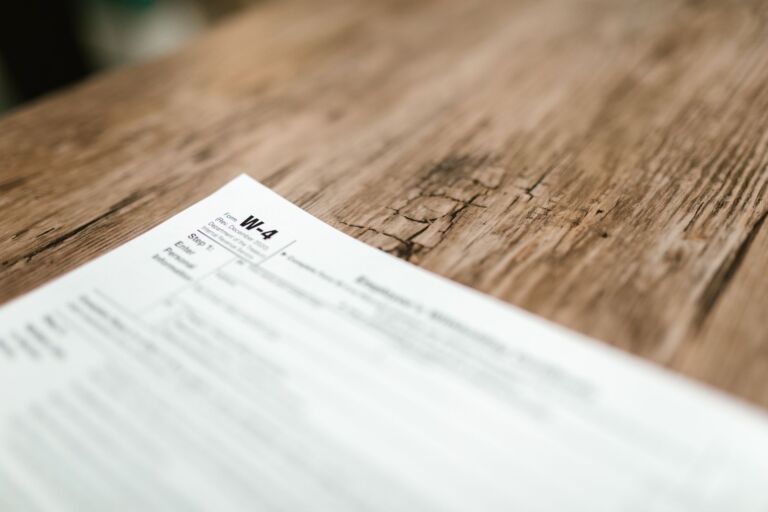 Gros plan d'un formulaire W-4 reposant sur une table en bois rustique, mettant en évidence les textures.