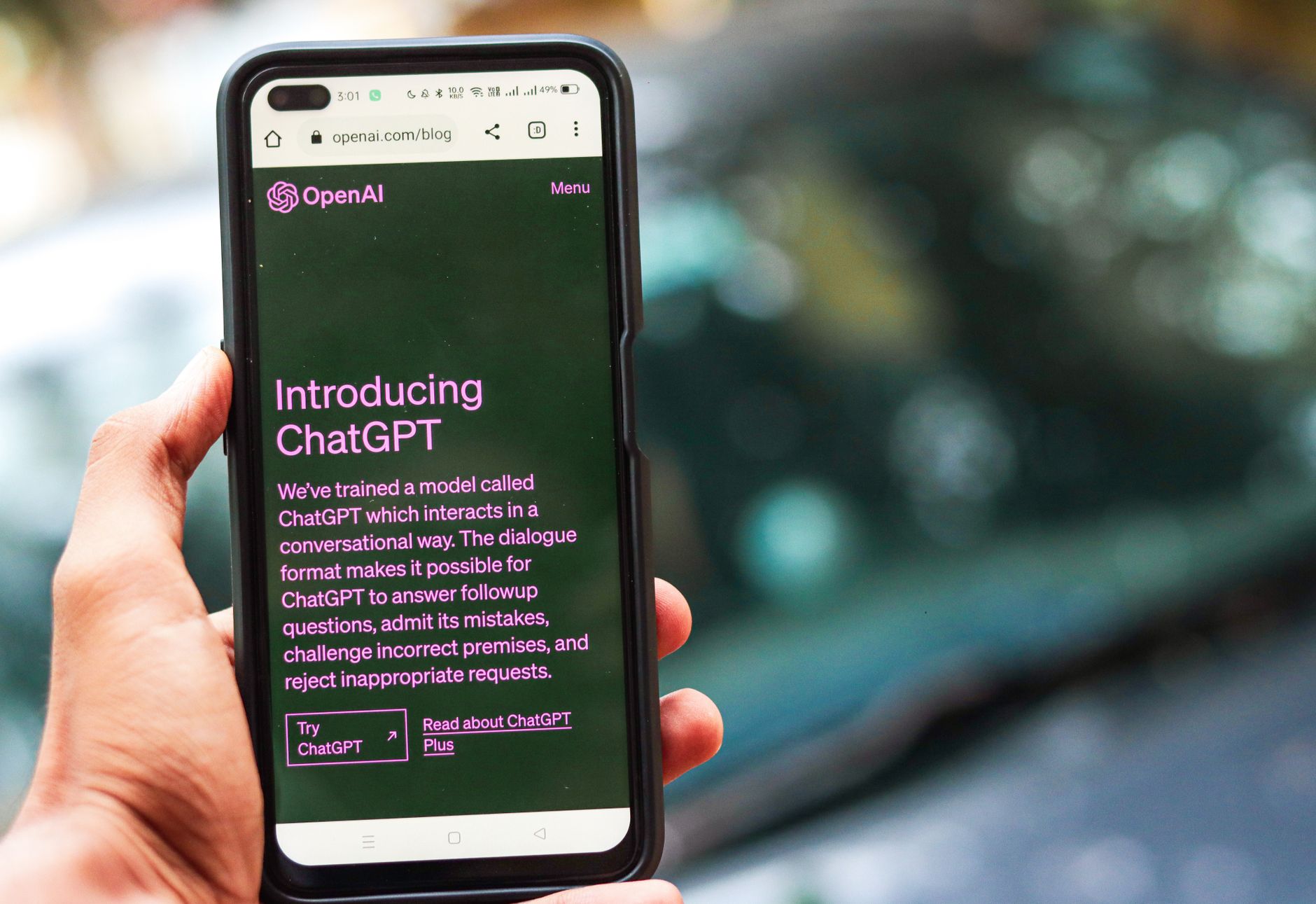 Gros plan sur un smartphone affichant les détails de ChatGPT sur le site d'OpenAI, tenu par une personne.