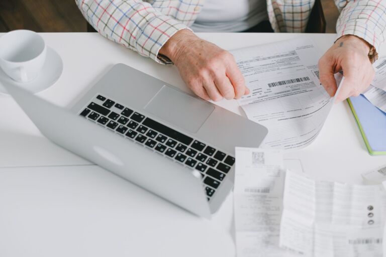 Gros plan sur des mains organisant des documents sur un bureau avec un ordinateur portable.