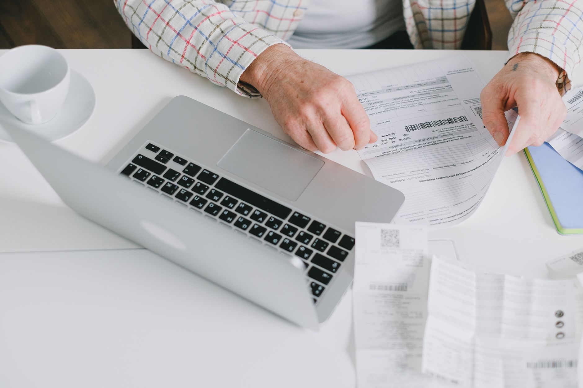 Gros plan sur des mains organisant des documents sur un bureau avec un ordinateur portable.