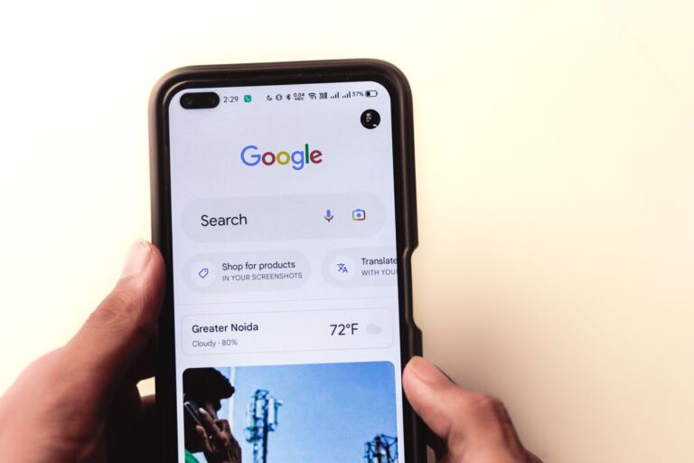 Gros plan sur une main tenant un smartphone avec la recherche Google affichée à l'écran.