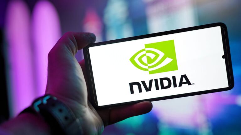 Gros plan d'une main tenant un smartphone affichant le logo NVIDIA sur l'écran avec un arrière-plan flou.