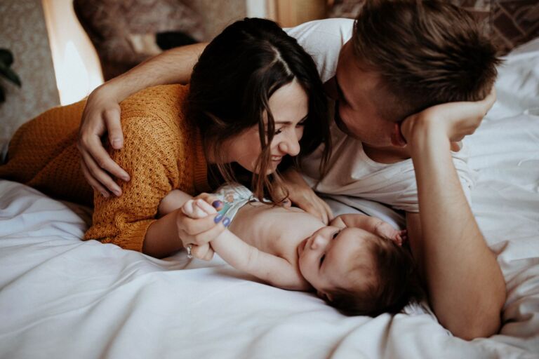 Un moment de famille joyeux avec des parents jouant avec leur bébé sur un lit, mettant en avant l'amour et la connexion.