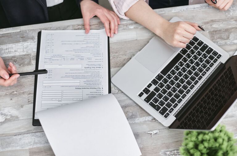 Deux personnes collaborant sur des documents et un ordinateur portable dans un bureau moderne.