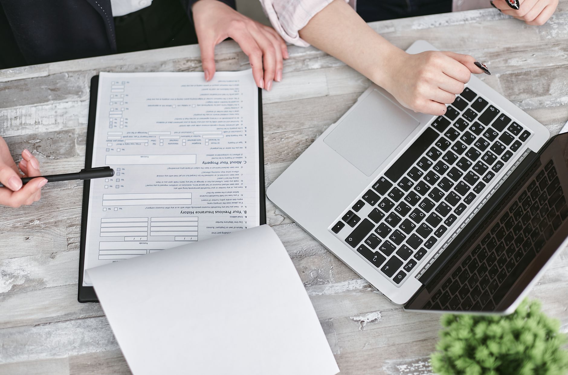 Deux personnes collaborant sur des documents et un ordinateur portable dans un bureau moderne.