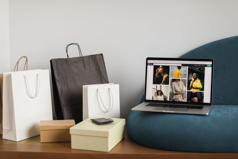 Ordinateur portable affichant un site de commerce électronique de mode à côté de sacs de shopping, idéal pour des thèmes de shopping en ligne.